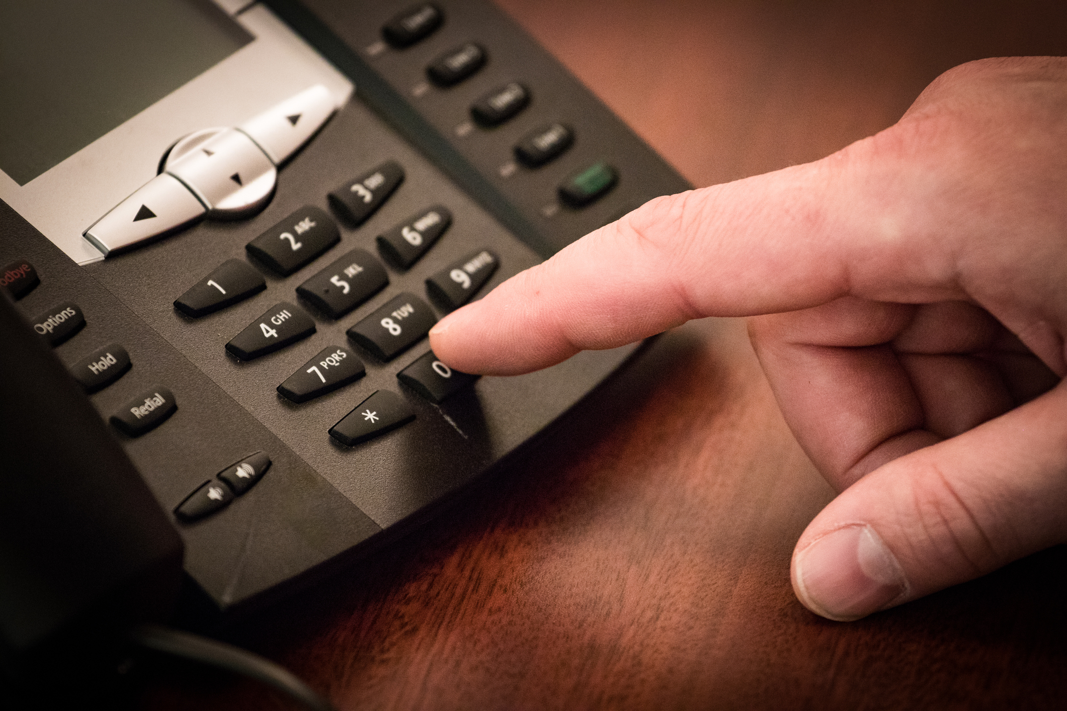 A finger dialing on a phone for what is a toll-free number
