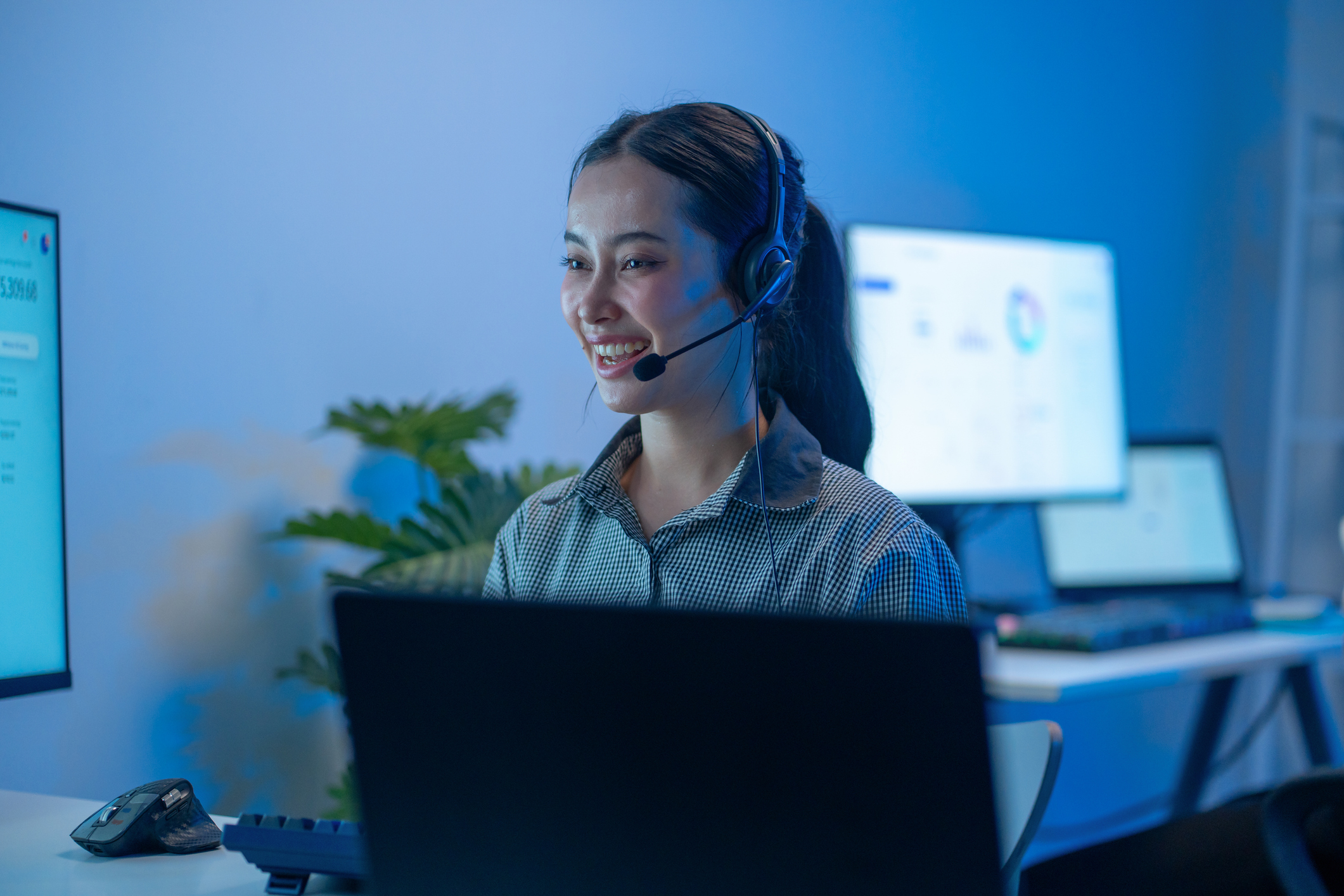 A professional answering service agent helps a caller in a corporate setting with blue lighting for the-impact-of-AI-on-answering-services blog.